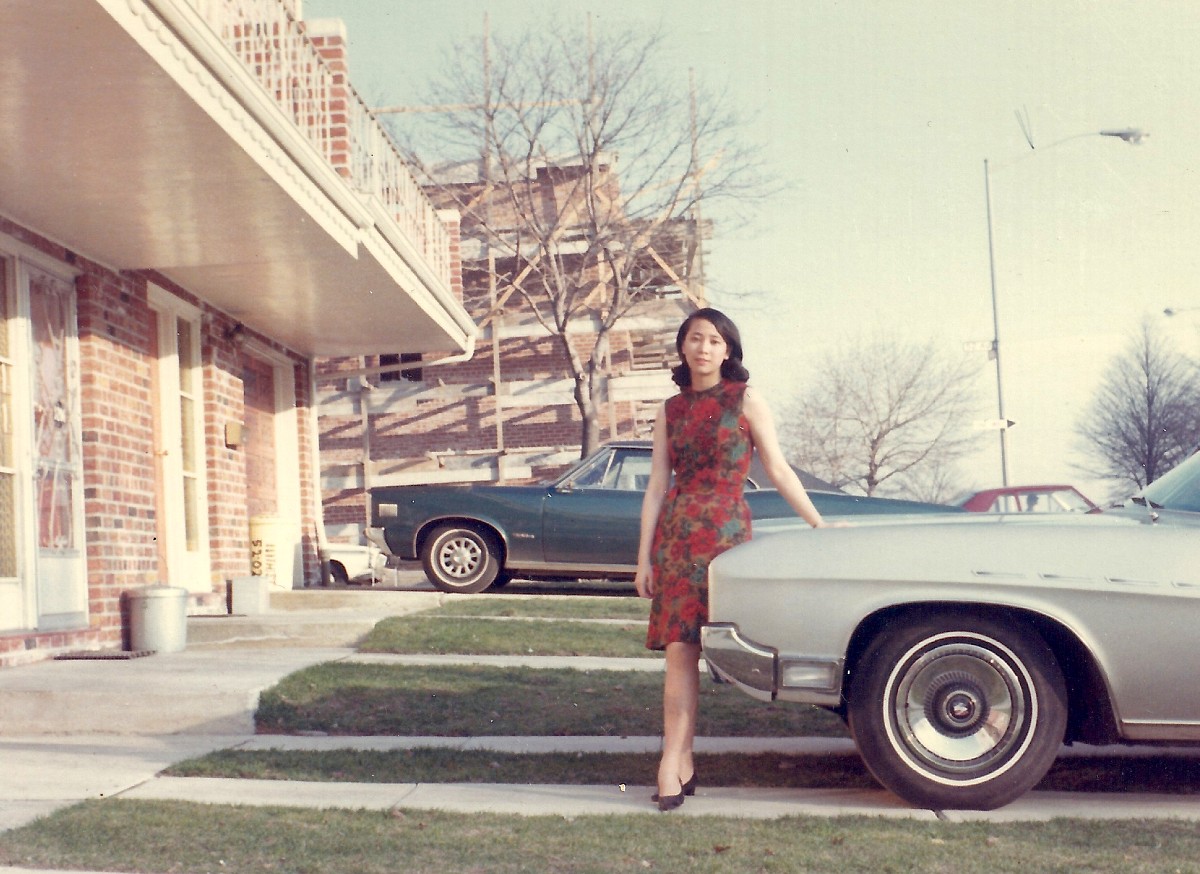Young Asian woman in dress standing next to Buick car 1960s